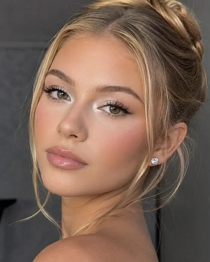 Teint lumineux et regard doux, chignon flou aux mèches libres