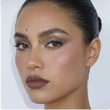 Maquillage de soirée aux yeux doux et lèvres prune, chignon bas lisse