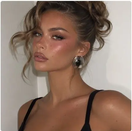 Chignon flou, teint bronzé lumineux et gloss, portrait de soirée